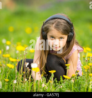 Petite fille dans le casque sur un pré vert. Banque D'Images