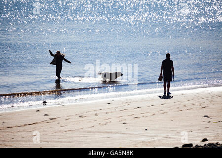 Homme et femme couple avec leur chien appréciant le soleil d'été sur la plage à la station balnéaire de Llandudno, au Pays de Galles, Royaume-Uni Banque D'Images