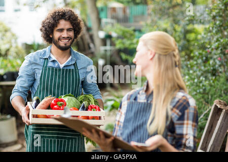 Jardinier à la femme à l'homme tout en maintenant la caisse de légumes Banque D'Images