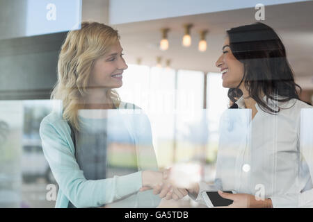 Businesswomen shaking hands in office Banque D'Images
