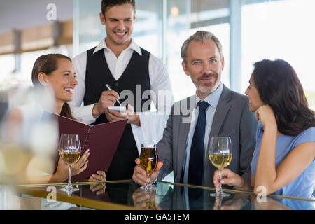 Waiter taking l'ordre d'un homme d'affaires et de ses collègues Banque D'Images