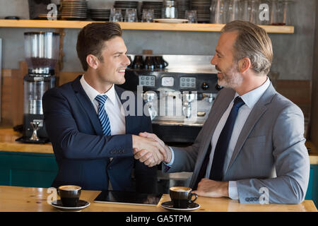 Businessmen shaking hands in cafC) Banque D'Images