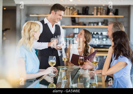 Waiter taking l'ordre d'un homme d'affaires et de ses collègues Banque D'Images