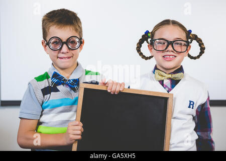 Portrait of smiling school kids holding slate in classroom Banque D'Images