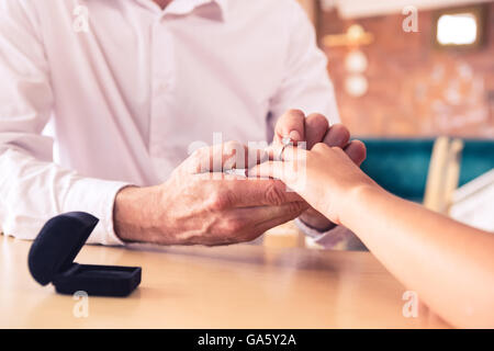 Man putting bague de fiançailles sur womans finger Banque D'Images