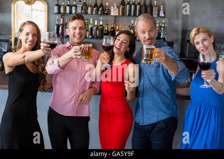 Groupe d'amis holding verres de bière et vin Banque D'Images