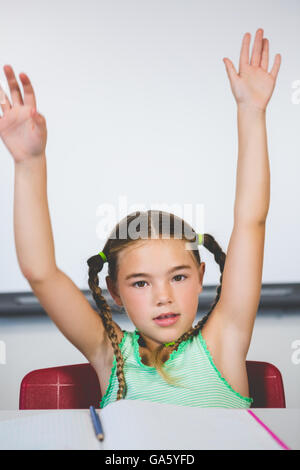 Portrait de lycéenne raising her arms in classroom Banque D'Images