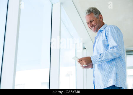 Low angle view of smiling man using phone Banque D'Images