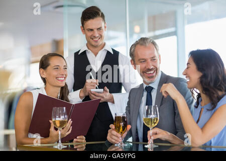 Waiter taking l'ordre d'un homme d'affaires et de ses collègues Banque D'Images