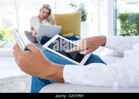 Portrait de l'homme à l'aide de tablet while woman holding laptop Banque D'Images