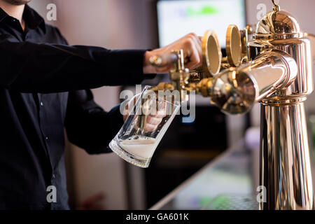 Bartender pouring beer de robinet dans verre pinte Banque D'Images