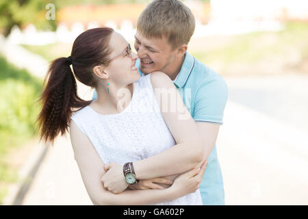 Beau jeune couple hugging étroitement les uns les autres de rire et de se regarder dans la rue. Un couple dans l'amour de marcher Banque D'Images