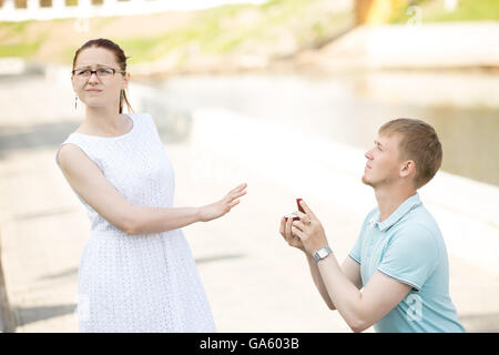 Femme refusant proposition de mariage. De graves beau jeune homme debout sur son genou offrant une boîte avec bague de fiançailles Banque D'Images