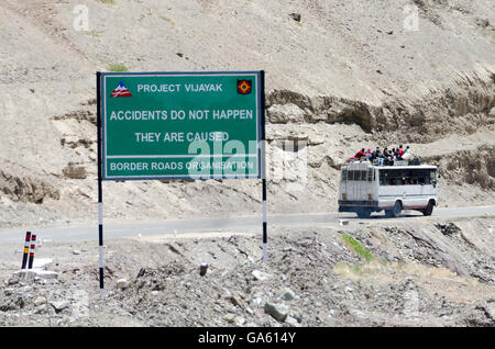 Bus avec les gens sur le toit en passant la sécurité routière signe sur Leh Ladakh Road, à Srinagar, Jammu-et-Cachemire, en Inde. Banque D'Images