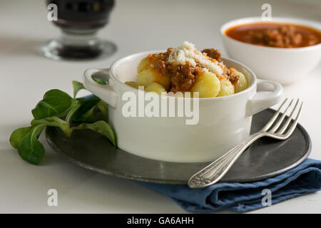 Maison traditionnelle gnocchi de pommes de terre avec la purée de tomates et le parmesan râpé dans un bol blanc Banque D'Images