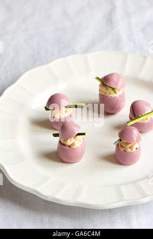 Oeufs de caille farcis au fromage à la crème, teintes avec le jus de betterave, sur la plaque de l'osier Banque D'Images