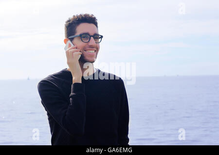 Casual young hispanic man en utilisant un smartphone outdoors Banque D'Images