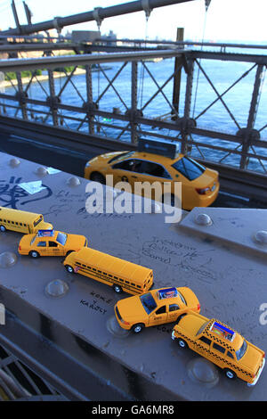 Taxi jaune disques durs sur le pont de Brooklyn à New York sous une collection de miniatures de souvenirs d'emblématique des taxis. Banque D'Images