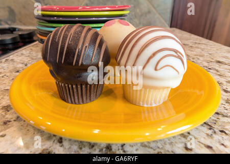 Cupcakes desserts sucrés sur plaque jaune assis sur un comptoir de cuisine en granit Banque D'Images