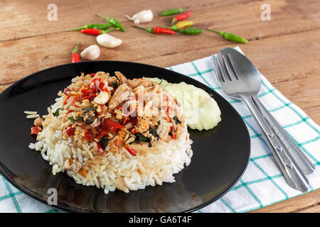 Garni de riz sauté de viande de crabe et le basilic dans un plat noir sur blanc bois Banque D'Images