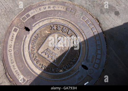 Un couvercle de vidange dans la rue arborant les armoiries de la ville de Gdansk et crest à Gdansk, Pologne Banque D'Images