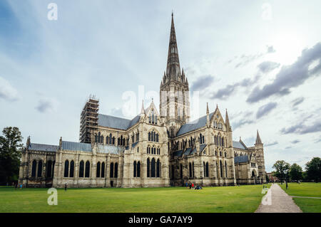 Salisbury, Royaume-Uni - 16 août 2015 : vue extérieure de la cathédrale de Salisbury avec les touristes dans l'herbe un jour nuageux. Banque D'Images