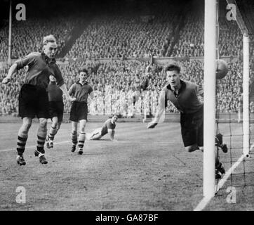 Billy Wright (l) de Wolverhampton Wanderers, Terry Springthorpe (deuxième à gauche) et le gardien de but Bert Williams (r) ne peuvent pas empêcher la balle de se rendre à l'arrière du filet.Ken Chisholm (c), de Leicester City, est en passe du regarder. Banque D'Images