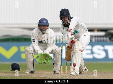 John Crawley, du Hampshire, joue sur la défensive, sous la surveillance du gardien de cricket du Lancashire, Luke Sutton, lors d'un match de la Liverpool Victoria County Championship Division One, au terrain de cricket d'Old Trafford, à Manchester. Banque D'Images