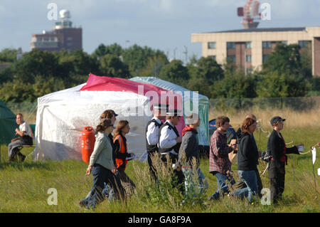 Les manifestants contre une troisième piste de l'aéroport d'Heathrow traversent leur camp de protestation avec des policiers qui sont arrivés pour inspecter le site. Banque D'Images