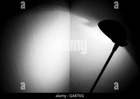 Lampe de lecture noire illumine le coin de la chambre peinte en blanc. La lumière et les ombres sur place Banque D'Images