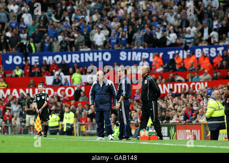 Le directeur de Chelsea Avram Grant (à gauche) et l'assistant Steve Clarke (au centre) regardent leur équipe comme une bannière dans la foule affiche le soutien des fans pour l'ancien directeur Jose Mourinho lors du match de la Barclays Premier League à Old Trafford, Manchester. Banque D'Images