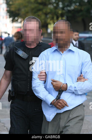 REMARQUE : FACES PIXÉLISÉES POUR PROTÉGER L'IDENTITÉ. Les agents d'immigration arrêtent un homme à la suite d'un raid sur un collège soupçonné de faux élèves à Stratford, dans l'est de Londres. Banque D'Images