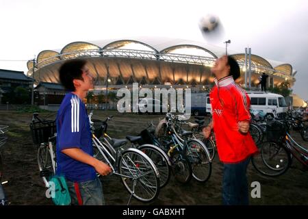 Deux fans de football japonais vêtus d'une équipe nationale japonaise le maillot et le maillot Manchester United jouent le tennis de tête en dehors du Stade Big Swan à Niigata Banque D'Images