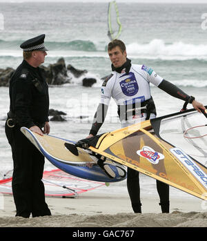 Le policier local Danny Lapsley de la police de Strathclyde, qui est le seul officier sur l'île de Tiree, parle avec le windsurfeur finlandais Tuomo Naalisvaara, alors qu'il était sur la plage de Balevullin sur l'île de Tiree. Banque D'Images