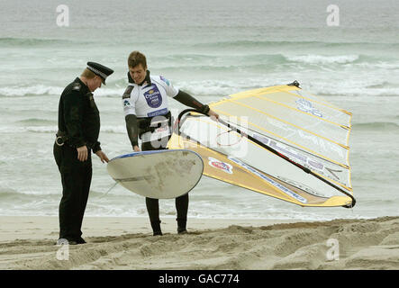 Danny Lapsley, policier local de la police de Strathclyde, s'entretient avec Tuomo Naalisvaara, le windsurfeur finlandais, alors qu'il était sur la plage de Balevullin sur l'île de Tiree. Banque D'Images