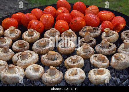 Dans les légumes de sel, d'épices et de la cuisson sur gril char, blanc champignons portobellos et petites tomates rouges Banque D'Images