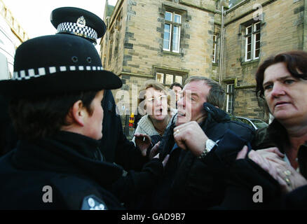 Le père de Vicky Hamilton Michael Hamilton (deuxième à partir de la droite) est retenu par la tante de Vicky Linda (troisième à partir de la droite) et sa femme Christine (à droite) alors que Peter Tobin quitte le tribunal du shérif de Linlithgow à West Lothian après qu'il ait été accusé du meurtre de Vicky Hamilton. Banque D'Images