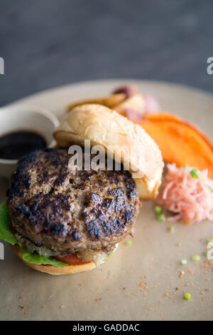 Un hamburger sain et de haute qualité, maigre, dans du pain fait maison, servi avec des frites de patate douce et des quartiers de pommes de terre, pas de personne, gros plan, fond neutre Banque D'Images