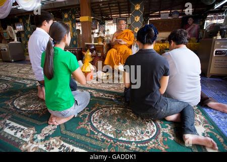 Asie, Thaïlande, Chiang Mai, Wat Doi Kham (Temple d'Or), moine bénédiction des gardiens de temple, les gardiens de temple faisant le mérite / payant le respect, vie familiale thaïlandaise Banque D'Images