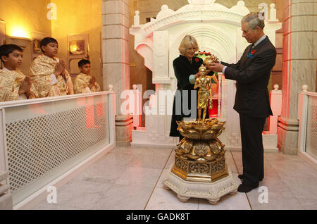 Le prince de Galles (à droite) et la duchesse de Cornouailles (à gauche) déversent l'eau sainte sur une figure de Murti lors d'une visite au temple Shri Swaminarayan à Neasden, dans le nord-ouest de Londres. Banque D'Images