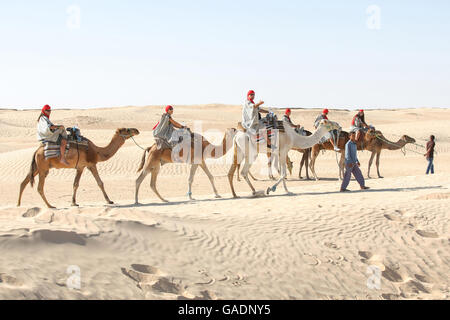 Des bédouins les touristes sur des chameaux à court-circuit touristique autour du début du désert du Sahara à Douz, Tunisie. Banque D'Images