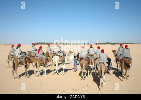 Des bédouins les touristes sur des chameaux à court-circuit touristique autour du début du désert du Sahara à Douz, Tunisie. Banque D'Images