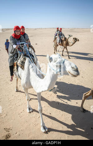 Des bédouins les touristes sur des chameaux à court-circuit touristique autour du début du désert du Sahara à Douz, Tunisie. Banque D'Images