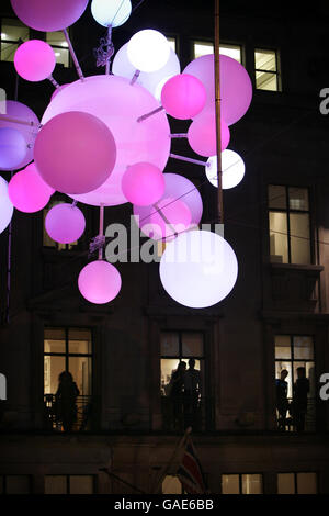 Les employés regardent depuis leurs fenêtres les lumières de Noël de Regent Street, Londres, qui sont allumées. Cette année, les lumières étaient inactives, s'allumant lorsque les gens marchaient sous elles. Banque D'Images
