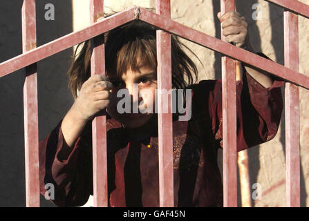 Un enfant regarde à travers la barrière d'une nouvelle école à Lashkar Gah, en Afghanistan, l'un des nombreux nouveaux projets d'aide financés par le gouvernement britannique. Banque D'Images