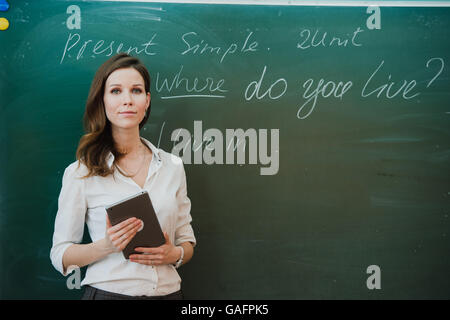 Young Female Teacher With Digital Tablet In Classroom. Banque D'Images