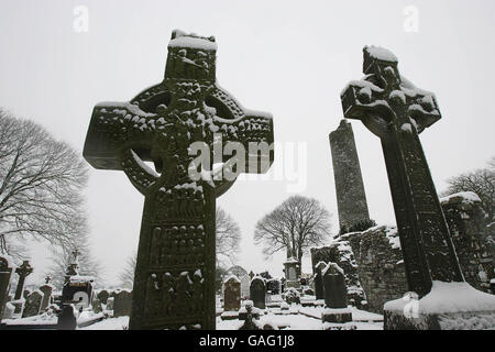 La neige couvre deux croisements celtiques à la tour ronde de Monasterboice dans le comté de Louth. Banque D'Images