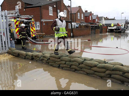 Les résidents du Toll Bar, près de Doncaster, observaient avec inquiétude aujourd'hui que l'eau de crue suite à une pluie torrentielle a ramené les inondations dans la région alors que les pompiers ont érigé des barrières pour sacs de sable et ont pompé des propriétés inondées. Banque D'Images