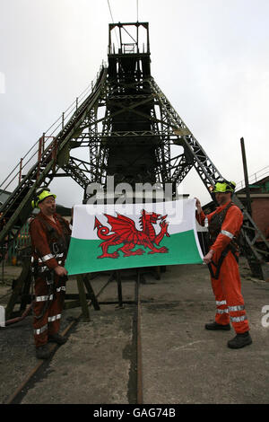 Les mineurs Garry Cutland et Billy Teague loft le drapeau gallois alors qu'ils terminent leur dernier quart de travail à la mine de charbon Tower à Hirwaun, Mid Glamorgan, pays de Galles. Banque D'Images