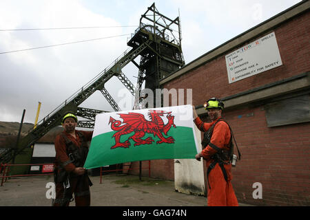 Les mineurs Garry Cutland et Billy Teague loft le drapeau gallois alors qu'ils terminent leur dernier quart de travail à la mine de charbon Tower à Hirwaun, Mid Glamorgan, pays de Galles. Banque D'Images